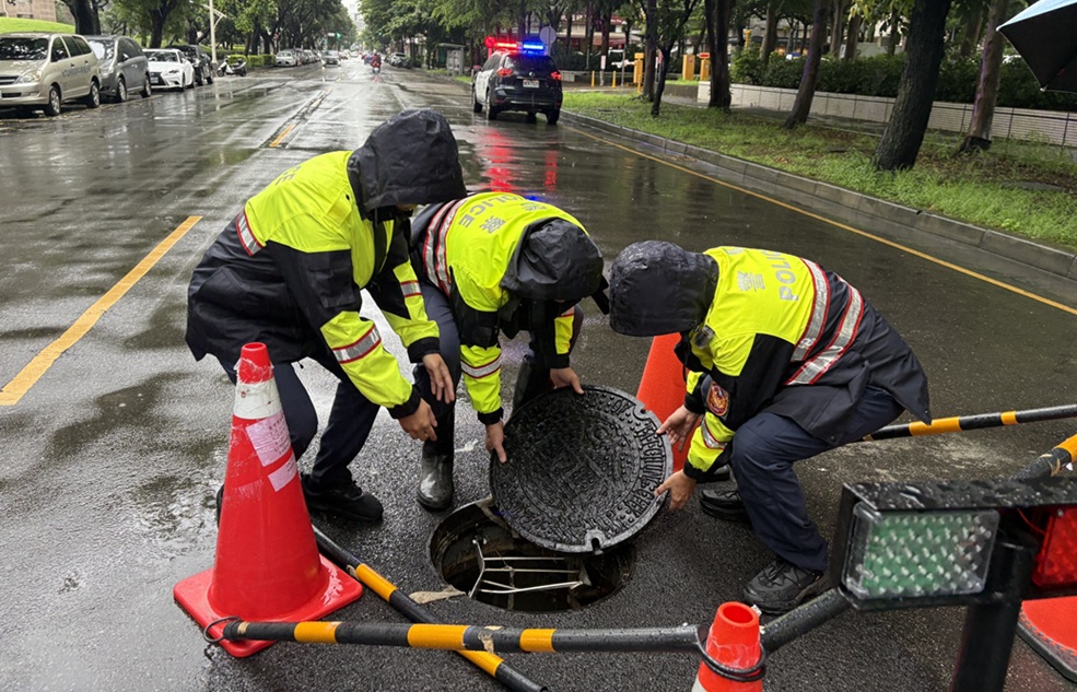 ▲圖說:中市文心南七路上人孔蓋扛不住水流而浮起,南屯所員警緊急以三角錐警示,並重新將人孔蓋固定 (圖/台中市政府 提供)