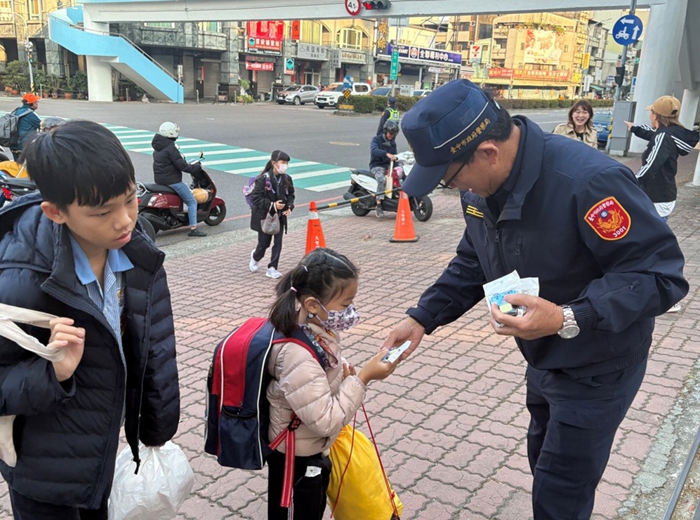 ▲圖說：第三警分局長謝有筆在校門口發放精美宣導小物「多功能充電鑰匙扣燈」            （圖／台中市政府 提供）