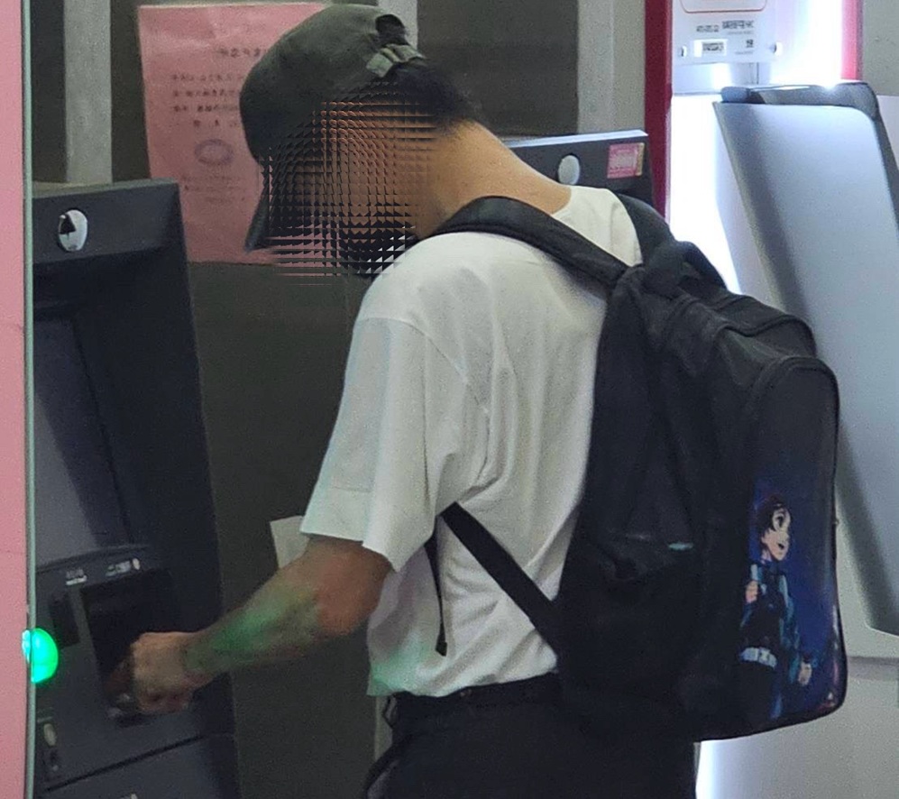 ▲圖說:61歲周姓車手身揹《鬼滅之刃》背包,一接獲詐團指示立即前往ATM領款 (圖/台中市政府 提供)